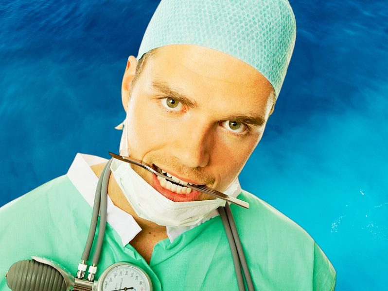 Scary looking doctor with scalpel in mouth prepared to circumsise